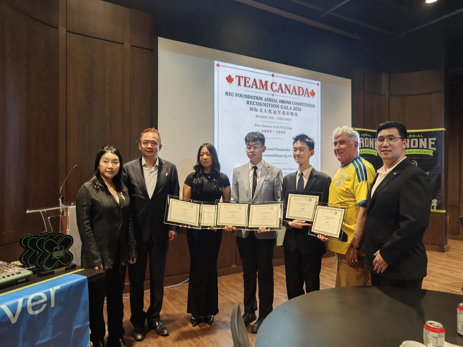 The team on stage at the REC Foundation Aerial Drone Competition Recognition Gala, holding framed certificates under a banner reading TEAM CANADA.